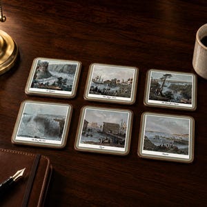 May include: A set of six square coasters with rounded corners, each featuring a distinct historical landscape illustration with a white border and a dark frame. The prints depict various scenes including waterfalls, coastal harbours, and ships.