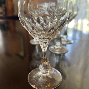 Peut inclure: Un ensemble de verres à pied en verre transparent présentant un motif à facettes en diamant sur la partie inférieure du calice et un pied à plusieurs pans. Les verres ont une base ronde et un bord supérieur lisse et brillant.