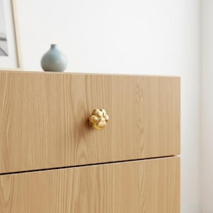 Puede incluir: Un letrero de madera hecho a mano con la palabra "Welcome" escrita a mano. El letrero está pintado de blanco con un acabado envejecido, y una pequeña hoja verde está adherida en la parte superior. Diseñado para uso interior o exterior.