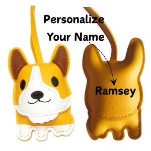 May include: A yellow and white corgi-shaped keychain with brown accents. The keychain has a leather strap and the text "Personalize Your Name" is above the keychain. The name "Ramsey" is written on the back of the keychain.