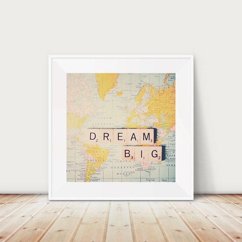 May include: A vintage world map with the phrase "DREAM BIG" spelled out in letter tiles. The tiles are arranged in a line across the map, with the word "DREAM" above the word "BIG".