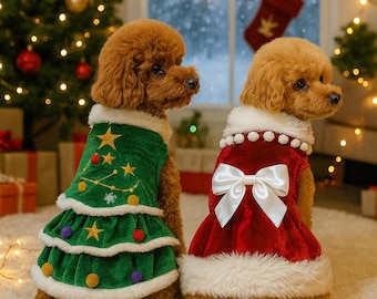 May include: Two brown dogs wearing Christmas outfits. One dog is in a green dress with a Christmas tree design, and the other is in a red dress with a white bow. The background includes a Christmas tree and a snowy window.