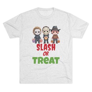 May include: A light gray t-shirt featuring a graphic of three cartoon characters dressed as horror movie villains, each holding a trick-or-treat basket. The text "SLASH OR TREAT" is printed below the characters in red and green.
