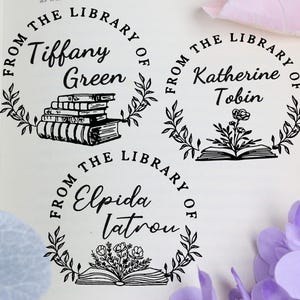 May include: Three circular library stamps with the text "From the Library of" and individual names: Tiffany Green, Katherine Tobin, and Elpida Iatrou. Each stamp features a different illustration: books, a flower, and a bouquet.