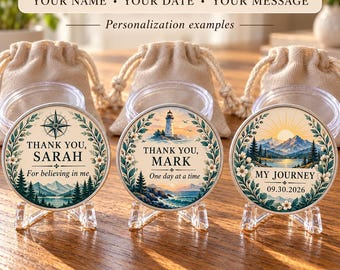 May include: Three circular metal tokens displayed on clear plastic stands, each featuring a unique illustration of a landscape, a floral border, and personalized text including "THANK YOU, SARAH", "THANK YOU, MARK", and "MY JOURNEY 09.30.2026".