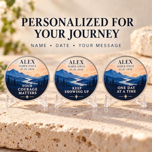 Può includere: Tre gettoni di sobrietà circolari in metallo su supporti trasparenti, raffiguranti un paesaggio montano all'alba, il testo "ALEX SOBER SINCE 01.01.2026" e le frasi "YOUR COURAGE MATTERS," "KEEP SHOWING UP," e "ONE DAY AT A TIME."