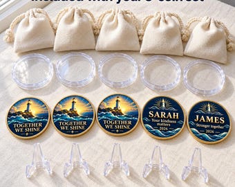 May include: A 5-coin set including five beige drawstring pouches, five clear circular coin capsules, and five clear plastic display stands. The coins feature lighthouse illustrations with text reading TOGETHER WE SHINE, SARAH Your kindness matters 2026, and JAMES Stronger together 2026.