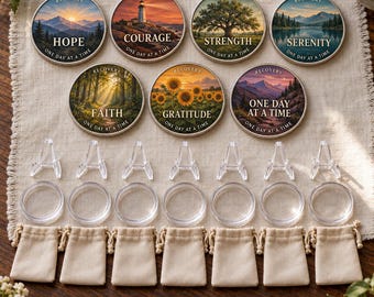 May include: Seven circular recovery coins featuring nature-themed illustrations and words like Hope, Courage, Strength, Serenity, Faith, Gratitude, and One Day at a Time. Includes seven clear plastic display stands, seven protective capsules, and seven small beige pouches.