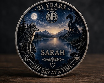 May include: A silver coin with a detailed landscape design. The coin features a wolf, a dragon, a lake, and mountains under a starry sky with a full moon. Text includes "21 YEARS", "SARAH", "ONE DAY AT A TIME", and the NA symbol.