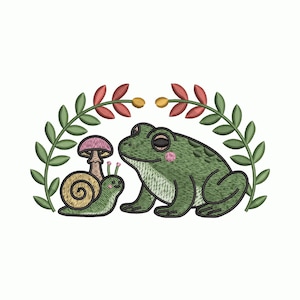 Puede incluir: Un diseño bordado con una rana verde y un caracol con una seta. La rana tiene mejillas rosas y está colocada junto al caracol. Un arco de hojas enmarca la escena, con detalles rojos y amarillos. El diseño está sobre un fondo blanco.