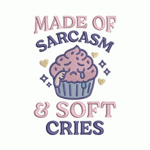 Op de afbeelding: Geborduurd ontwerp met een verdrietige cupcake met de tekst "MADE OF SARCASM & SOFT CRIES". De cupcake is roze met blauwe frosting en een blauwe cupcake-vorm. Gouden harten en blauwe sterren omringen de cupcake.