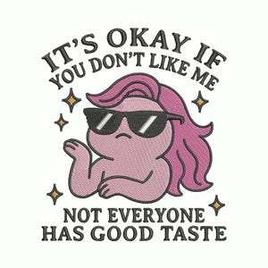 May include: Embroidered design featuring a pink character wearing sunglasses and pink hair. The text reads "IT'S OKAY IF YOU DON'T LIKE ME, NOT EVERYONE HAS GOOD TASTE" with star accents. The design is on a white background.