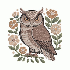 May include: An embroidered design featuring a brown owl with orange eyes, perched on a branch. The owl is surrounded by a wreath of tan flowers and green leaves, set against a white background.