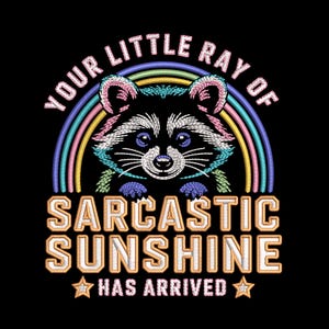 May include: Black graphic featuring a raccoon with a rainbow and the text "YOUR LITTLE RAY OF SARCASTIC SUNSHINE HAS ARRIVED". The raccoon has blue, pink, and white details. The text is in a gold color with a black background.