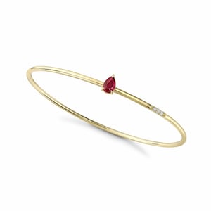 May include: A gold bangle bracelet featuring a pear-shaped, red gemstone and three small diamonds. The bracelet has a simple, elegant design, perfect for everyday wear. The gold has a polished finish.