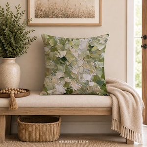 May include: A square throw pillow featuring an abstract oil painting design with thick, textured brushstrokes in various shades of sage green, olive, cream, and white. The pattern covers the entire front surface of the pillow in a dense, layered composition.