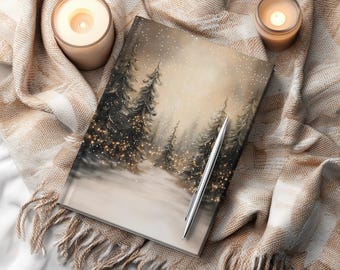 May include: A journal with a winter forest scene, a silver pen, and two lit candles on a beige blanket. The journal cover features a snowy landscape with evergreen trees and twinkling lights. The blanket has a fringed edge.