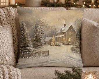 May include: A square throw pillow featuring a printed winter scene of a two-story house with snow-covered roofs, illuminated windows, and a glowing Christmas tree in the yard. The landscape includes snow-dusted pine trees and a wooden fence.