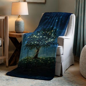 Puede incluir: Una manta azul oscuro con un diseño de árbol y luces brillantes, sobre un sillón blanco. La manta representa un cielo estrellado. El diseño crea una atmósfera cálida y acogedora.