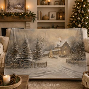 Könnte beinhalten: Eine weiche Wohndecke mit einem aufgedruckten Winterszenario, das ein verschneites Haus, hohe Tannen und einen Holzzaun zeigt. Das Design präsentiert ein warmes, leuchtendes Licht aus den Hausfenstern und einem kleinen Baum im Vorgarten.