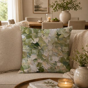 May include: A square throw pillow featuring an abstract oil painting design with thick, textured brushstrokes in various shades of sage green, olive, cream, and white. The pattern covers the entire front surface of the pillow in a dense, layered composition.