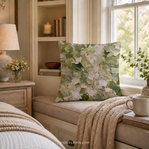 May include: A square throw pillow featuring an abstract oil painting design with thick, textured brushstrokes in various shades of sage green, olive, cream, and white. The fabric displays a visible canvas-like weave pattern throughout the surface.