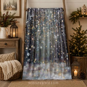 May include: A rectangular throw blanket featuring a printed winter forest scene with dark tree trunks, soft glowing bokeh lights, and white snowflakes scattered across the surface, creating a festive atmosphere with a deep blue and grey colour palette.