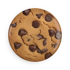 May include: A single, round chocolate chip cookie. The cookie has a golden-brown base with numerous dark chocolate chips of varying sizes embedded throughout. The cookie is set against a plain white background.