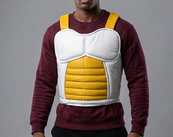 May include: A white, yellow, and black chest armor with shoulder straps. The armor has a white chest and shoulder pads, with a yellow midsection. The person in the image is wearing a maroon sweatshirt and black pants.