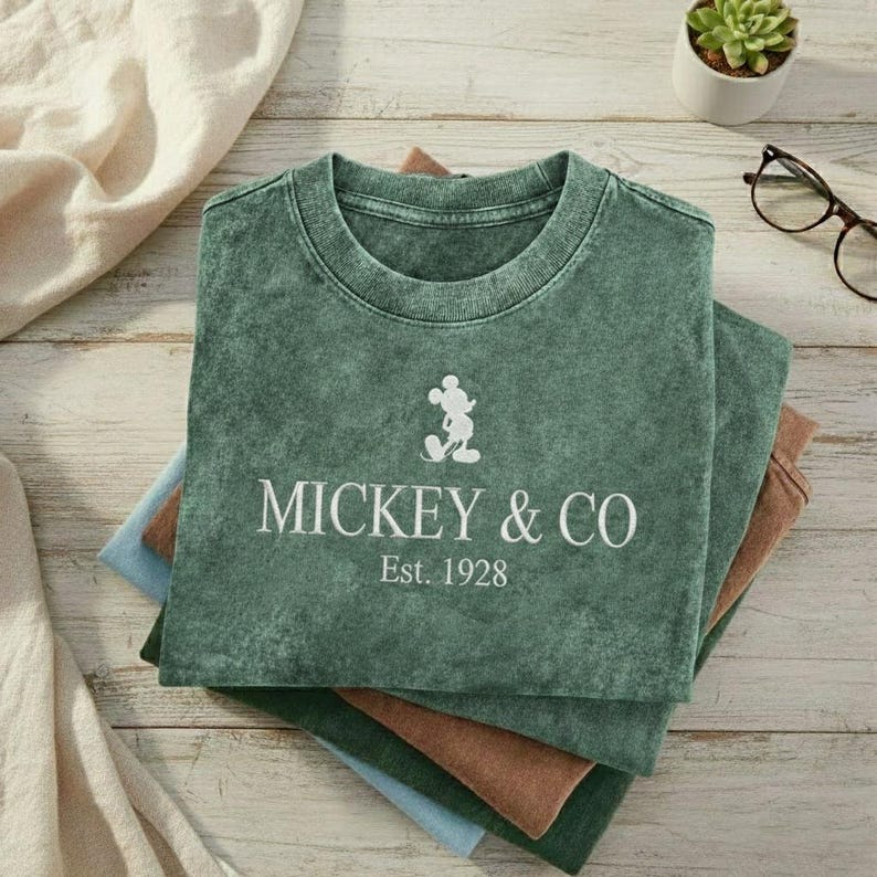 May include: A white ceramic mug with a black handle and the text "But First, Coffee" in a handwritten style. The mug is on a white surface. The mug is approximately 4 inches tall.