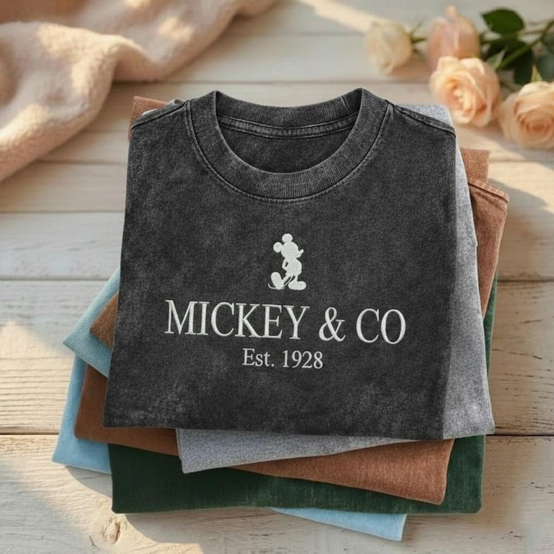 May include: A white ceramic mug with a black handle and the text "But First, Coffee" in a bold, black font. The mug is sitting on a wooden surface. The mug is approximately 4 inches tall.