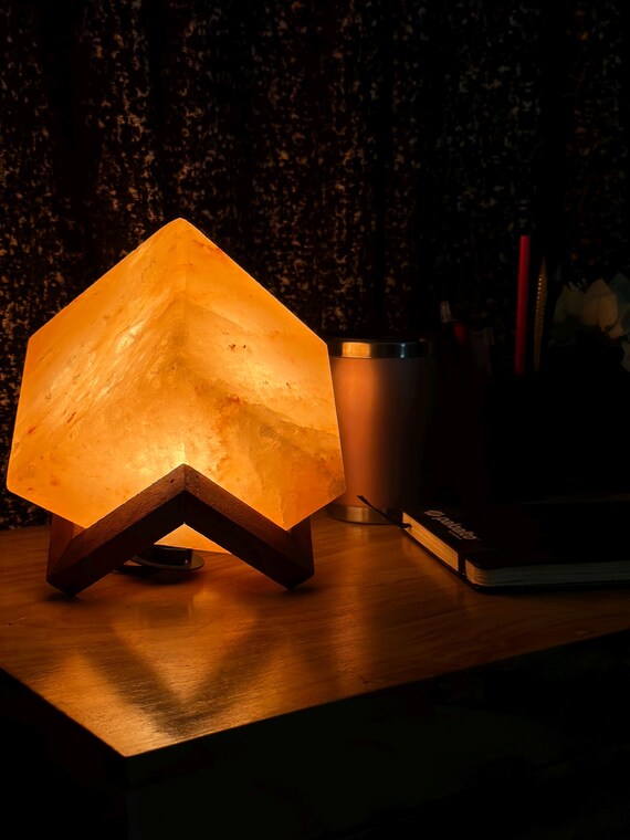 Illuminated Cubic Himalayan Salt Lamp on Wooden Stand .