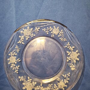 Puede incluir: Plato de cristal transparente con borde dorado y diseño floral de rosas. El plato presenta un delicado patrón de rosas y hojas alrededor del borde. Plato decorativo de estilo vintage.