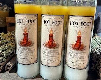 Könnte beinhalten: Drei hohe Glas-Kerzen mit gelbem Wachs, jede mit einem Etikett, das HOT FOOT PREPARED CANDLE, 4 LUNAS BOTANICA und eine Abbildung eines brennenden Fußes zeigt. Die Kerzen haben weißes Wachs am Boden und gelbes Wachs an der Oberseite.