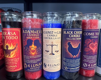 May include: A collection of glass jar candles with colorful wax and labels. The labels feature text and illustrations, including a silhouette of a person in flames, silhouettes of Adam and Eve, a scale, and a rooster. The candles are for spiritual purposes.