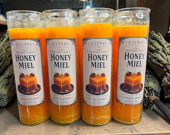 May include: Four tall cylindrical glass candles filled with bright orange wax. Each candle features a white label with the text 4 LUNAS BOTANICA, 7 DAY PREPARED CANDLE, HONEY MIEL, and an illustration of a honeycomb square with two bees.