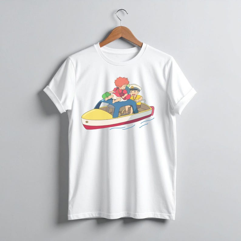 May include: White t-shirt featuring a colorful cartoon illustration of three characters in a yellow and red boat. The characters have red, yellow, and green hair and are wearing blue and yellow clothing. The boat is on blue water.