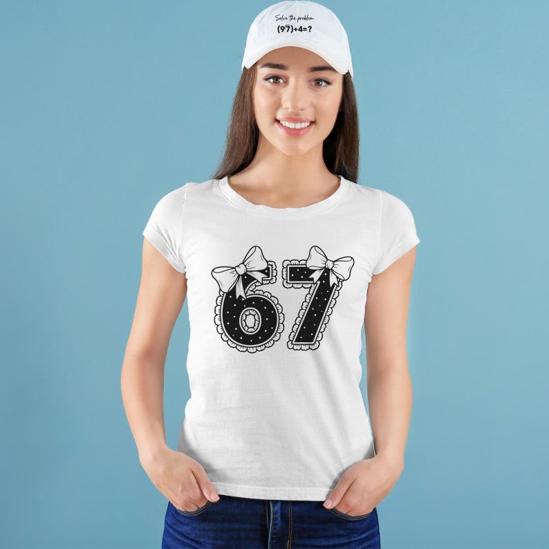 May include: White t-shirt with a black and white graphic of the numbers 6 and 7, each adorned with a bow. The shirt is paired with a white baseball cap that has the text "Solve the problem (97)+4=?" in black.