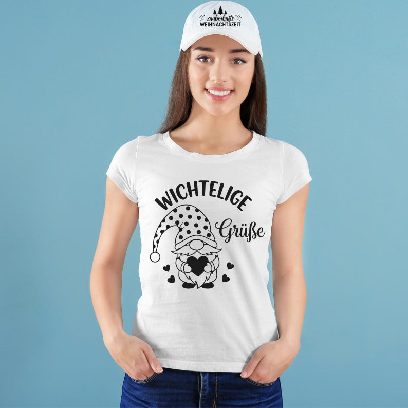 May include: White t-shirt with a black graphic of a gnome holding a heart, and the words "Wichtelige Gr&uuml;&szlig;e". A white baseball cap with the text "Zauberhafte Weihnachtszeit" is also visible.
