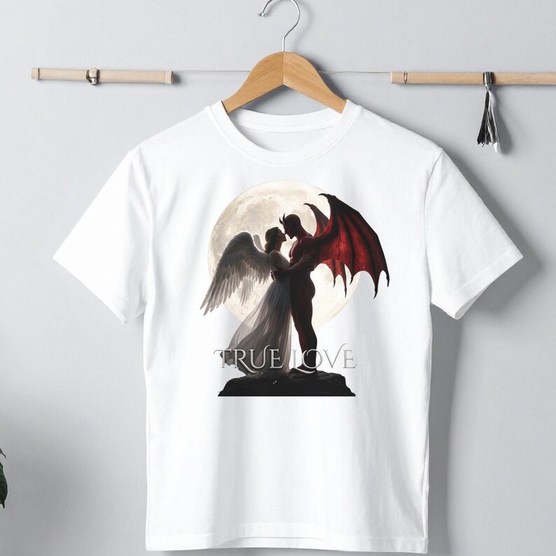 May include: A white short-sleeve t-shirt featuring a graphic print of an angel with white wings and a devil with red wings embracing in front of a large full moon. The text TRUE LOVE is printed in a serif font below the figures on a dark base.