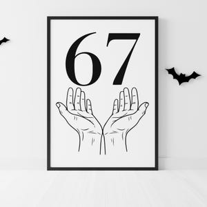 May include: Black framed print featuring the number 67 in bold black font above a detailed line drawing of two open hands. Two black bat silhouettes are on the white wall. The print is on a white background.