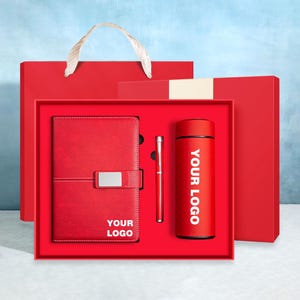 Könnte beinhalten: Ein rotes Geschenkset mit Notizbuch, Stift und Becher, alles in einer passenden roten Box. Das Notizbuch hat einen silbernen Verschluss und den Text "YOUR LOGO". Der Becher hat den Text "YOUR LOGO".