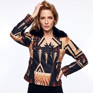 May include: A moto-style jacket featuring a geometric pattern in shades of black, tan, and burnt orange. The jacket has a black faux fur collar, long sleeves with zippered cuffs, and an asymmetrical front zipper closure with a notched lapel design.