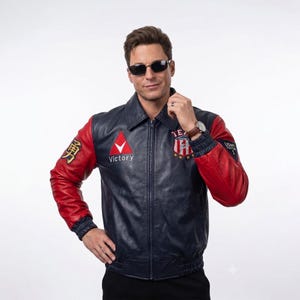 May include: A navy blue leather jacket with red sleeves, a front zipper, and a collar. The chest features a red triangle with the word Victory, and a shield emblem with the text Team Victory. The right sleeve has a gold character, and the left sleeve has a black patch with USNT Fighter 1.