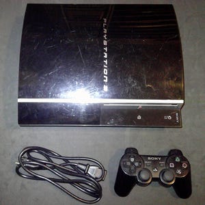 May include: A black PlayStation 3 game console with a glossy finish, featuring the text PLAYSTATION 3 on the top surface. Included is a black wireless game controller with Sony branding and a black power cable with a standard electrical plug.