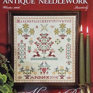 May include: A framed sampler and antique needlework quarterly magazine cover. The cover features a detailed cross-stitch design with floral and animal motifs, including deer and birds. The text reads "Sampler & Antique Needlework" and "Winter 2006".