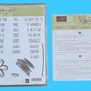 May include: A Stampin' Up! Sunshine Sayings clear stamp set in a plastic case with text including On One More Year, Happy Birthday, and Hello, alongside a separate instruction sheet for Big Shot dies with English and French text.
