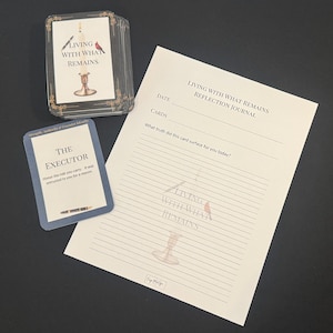 Puede incluir: Un juego de cartas y un diario con el texto "Living With What Remains". Las cartas tienen ilustraciones de una vela y un pájaro. Una carta dice "The Executor". El diario tiene páginas rayadas.
