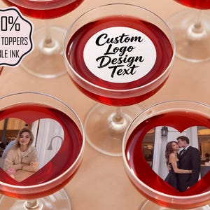 Könnte beinhalten: Mehrere Weingläser gefüllt mit roter Flüssigkeit, einige mit herzförmigen Ausschnitten, die Fotos zeigen. Ein Glas hat ein kreisförmiges Design mit dem Text "Custom Logo Design Text". Ein anderes hat einen Aufkleber mit der Aufschrift "100% Edible Toppers Edible Ink."