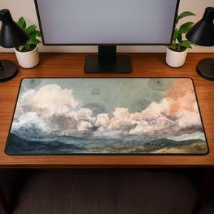 Puede incluir: Alfombrilla de escritorio rectangular con un diseño de paisaje en acuarela. El diseño muestra un cielo con nubes blancas y melocotón, una cordillera en azul y verde y detalles en espiral. Para el escritorio.